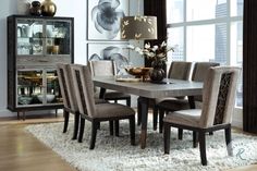 a dining room table and chairs in front of a large window with an area rug on the floor