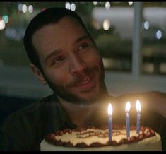 a man holding a birthday cake with lit candles