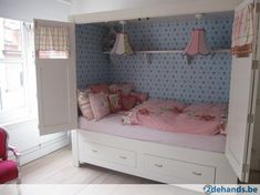 a bedroom with blue and pink wallpaper has a bed in the corner, two hanging lights above it