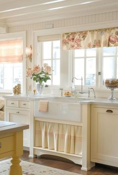 a kitchen with white cabinets and flowers on the window sill above the sink is shown