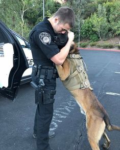 a police officer is hugging his dog in the parking lot