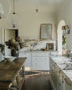 a large kitchen with marble counter tops and white cabinetry, along with wooden flooring