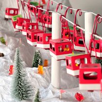 there are many red and white toy trains on the tracks with christmas trees in front of them