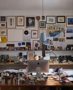 a desk with a laptop computer sitting on top of it next to a bunch of pictures