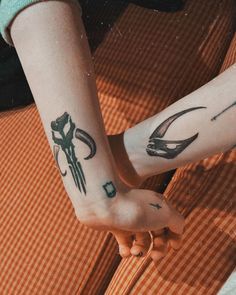 two people with tattoos on their arms holding hands