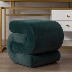 a green chair sitting on top of a wooden floor next to a white dresser and desk