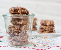 a glass jar filled with granola sitting on top of a table next to cookies