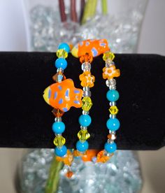 This bracelet is uniquely handmade. It includes semi precious stone blue striped agate, Yellow, orange and white swvarski crystals, porcelain fish, czech flower beads, matching glass beads, and custom czech and crystal charms. This is an easy-to-wear bracelet with no clasp just wrap around your wrist. This bracelet is made to fit most wrists because there is no clasp making it adjustable to each individual wrist. This would be a wonderful gift for yourself or others. Unique Adjustable Orange Bracelet, Unique Orange Adjustable Bracelet, Blue Wrap Bracelet With Colorful Beads For Gifts, Blue Wrap Bracelet With Colorful Beads As Gift, Unique Adjustable Czech Glass Beaded Bracelets, Adjustable Czech Glass Beaded Bracelets, Adjustable Czech Glass Bracelets For Gifts, Adjustable Czech Glass Bracelets As Gifts, Adjustable Czech Glass Bracelet As Gift