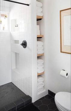 a white toilet sitting next to a walk in shower under a framed picture on the wall