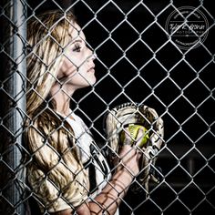 a woman holding a baseball glove behind a chain link fence