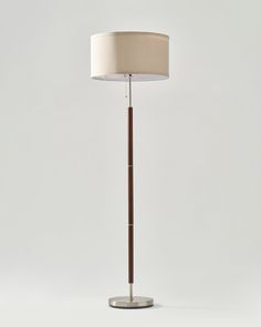 a floor lamp with a beige shade on it's side and a wooden base