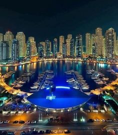 an aerial view of a city at night with boats in the water and high rise buildings