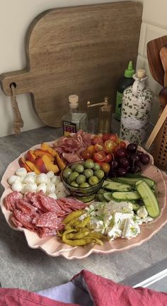 a platter filled with assorted meats and vegetables on a table next to a cutting board