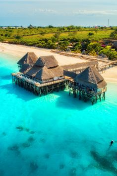 the water is crystal blue and clear with some huts on it's roof overhangs