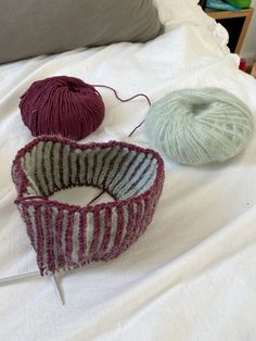 three balls of yarn sitting on top of a bed