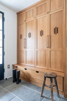 a room with wooden cabinets and stools next to a window on the wall,