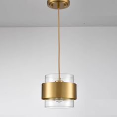 a gold and clear glass pendant light hanging from a ceiling fixture in a white room