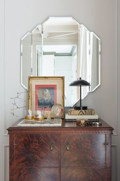 a dresser with a mirror, lamp and pictures on it