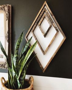 a potted plant sitting on top of a wooden table next to a framed mirror