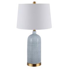 a blue glass table lamp with a white shade on the top and gold trim around the base