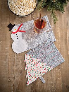 a wooden table topped with plates and bowls filled with food next to a christmas tree