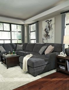 a living room with gray couches and white rugs on the hardwood flooring