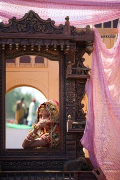 a person taking a photo in a mirror with a pink cloth draped over the window