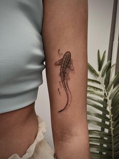 a woman's arm with a tattoo on it that has a fish in the water