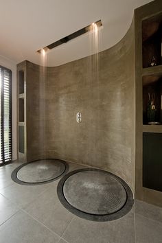 a bathroom with two circular rugs on the floor in front of a large shower