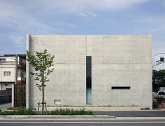 the building is made out of concrete and has a green tree in front of it