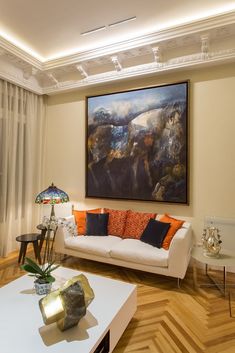 a living room filled with furniture and a painting hanging on the wall above it's windows