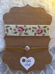 three beaded bracelets are on display in a cardboard box with a white heart