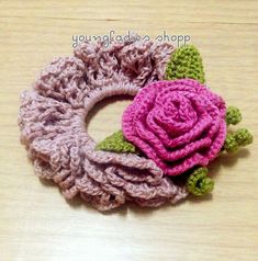 two crocheted flower hair clips sitting on top of a wooden table