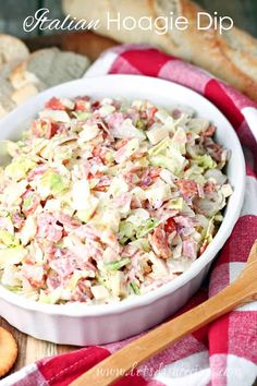 a white bowl filled with coleslaw next to sliced bread on a red and white checkered table cloth