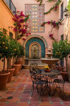 an outdoor patio with tables and chairs, potted plants on either side of the fountain