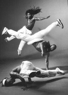 two men are doing acrobatic moves in the air while another man is on the ground