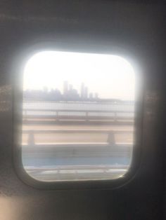 an airplane window with the view of a bridge and city in the distance as seen from inside