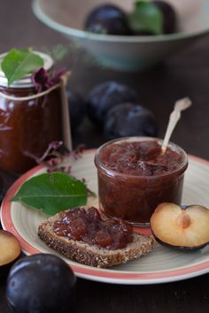 a plate with bread, jam and plums on it