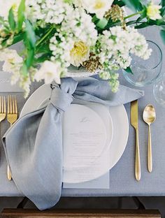 a place setting with silverware and white flowers