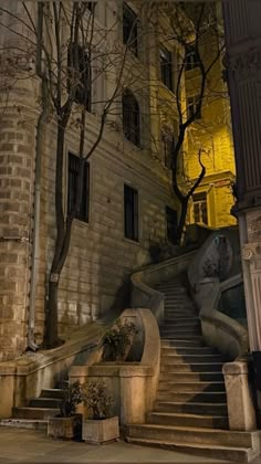 an old building with stairs leading up to the top floor and trees in front of it