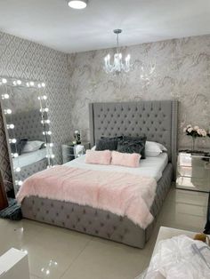 a bedroom with a bed, mirror and chandelier in the middle of it