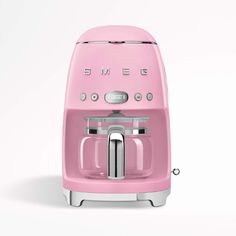 a pink coffee maker sitting on top of a white table