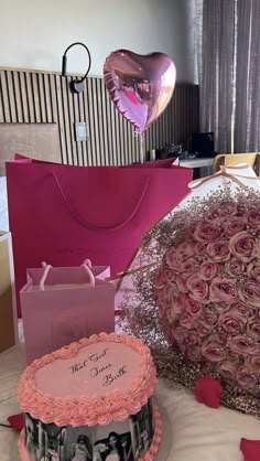 a table topped with two cakes covered in frosting next to pink bags and balloons