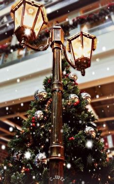 a christmas tree is lit up in the middle of a shopping mall with snow falling on it