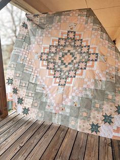 an old quilt hanging on the side of a wooden porch with wood flooring and railing