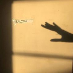 the shadow of a person's hand on a wall that says healin'6