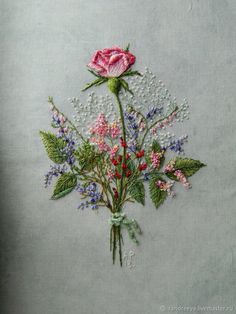 a bouquet of flowers is embroidered onto the side of a piece of cloth with beading