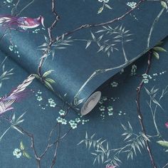 a blue wallpaper with birds and flowers on it's side, next to a roll of tape