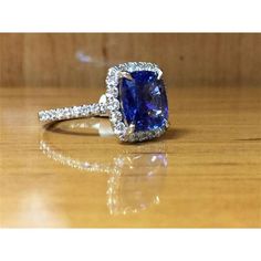 a blue and white diamond ring sitting on top of a wooden table