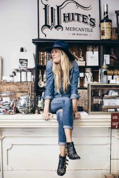 a woman sitting on top of a counter in front of a sign that says white's mercantile